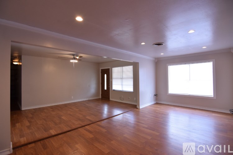 A spacious room with wooden floors and a ceiling fan.