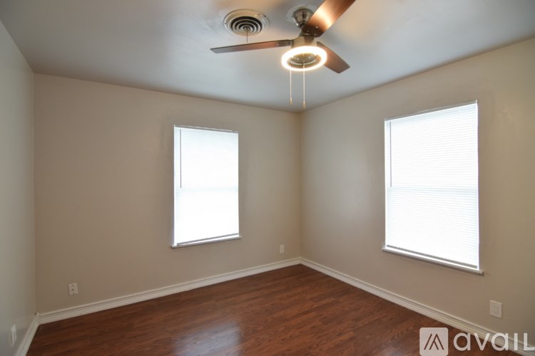 A room with a ceiling fan and two windows.