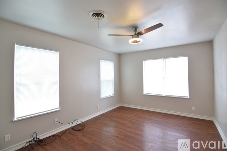 A room with a ceiling fan and two windows.