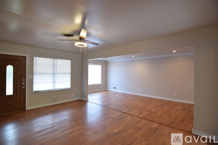 A spacious room with wooden floors and a ceiling fan.