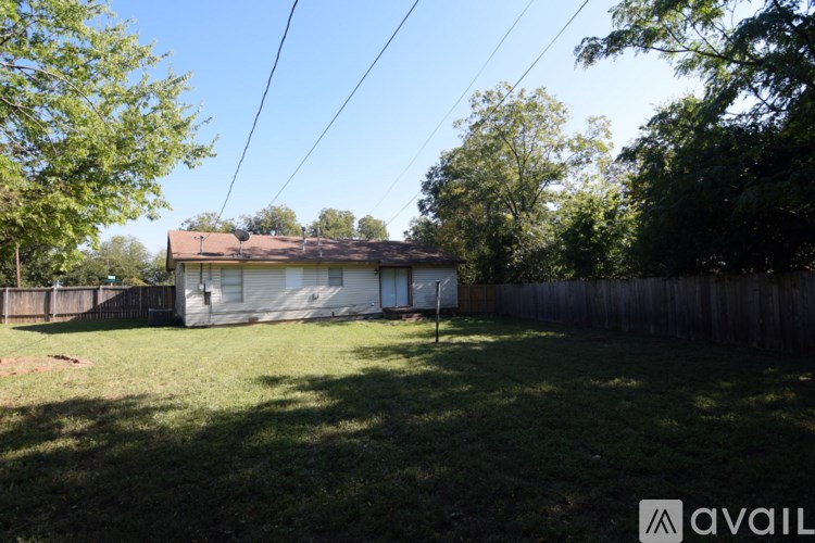 A backyard with a house, fence, and trees.