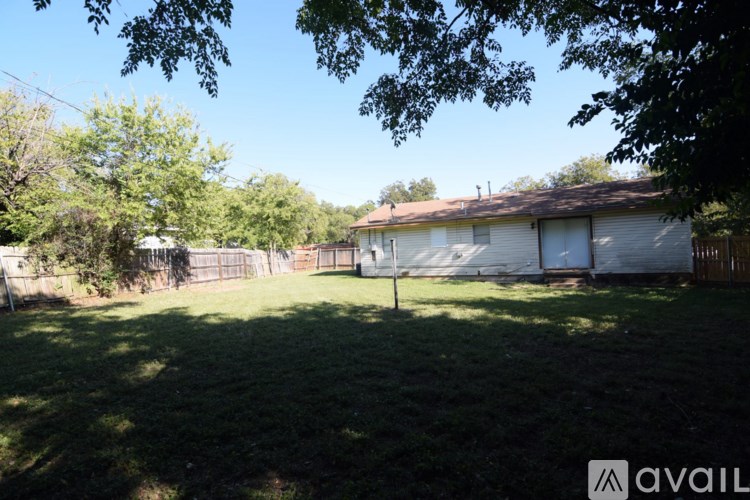 A backyard with a house, trees, and a fence.