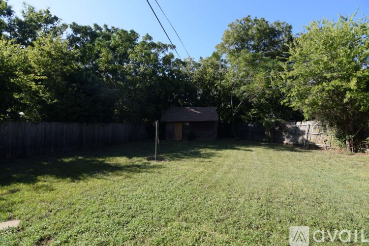 A backyard with a fence and a small building.