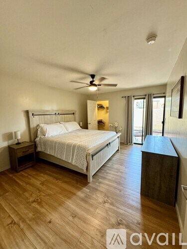 A bedroom with a large bed and wooden flooring.