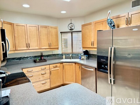 A kitchen with wooden cabinets and a stainless steel refrigerator.