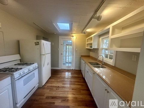 A kitchen with a white stove and wooden floors.