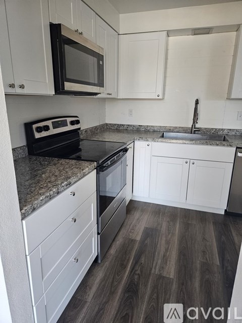A kitchen with white cabinets and a black stove top oven.