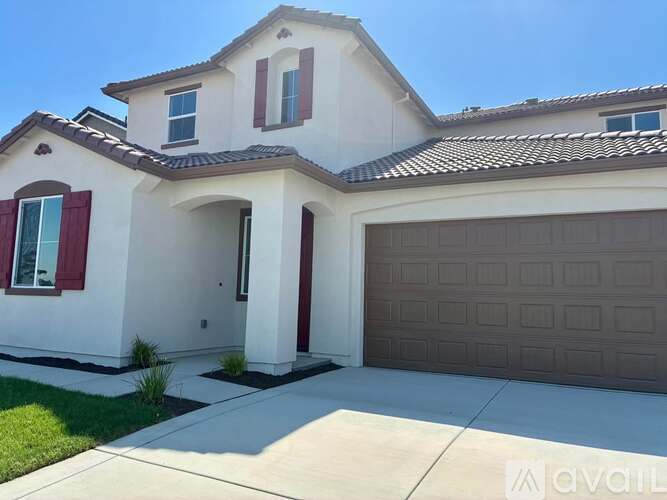 A two-story house with a garage door and a driveway.