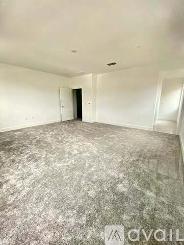 A spacious empty room with a doorway leading to another room.