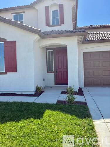 A white house with a red door and brown garage door.