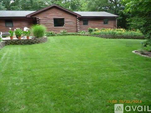 A house with a brown wooden exterior and a green lawn in front.