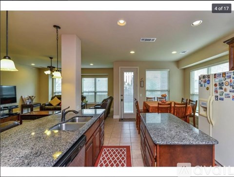 A kitchen with granite countertops and a refrigerator with magnets on it.