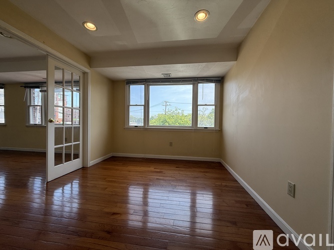 A spacious room with wooden floors and a large window.