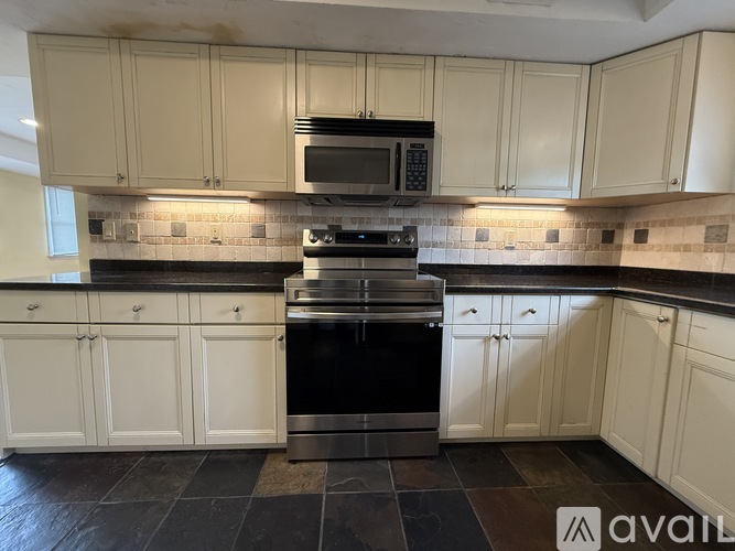 A kitchen with white cabinets and a black stove top oven.