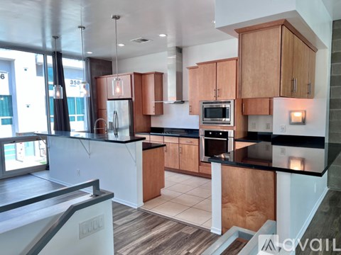 A modern kitchen with wooden cabinets and black countertops.