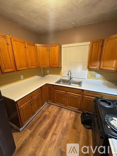 A kitchen with wooden cabinets and a black dishwasher.