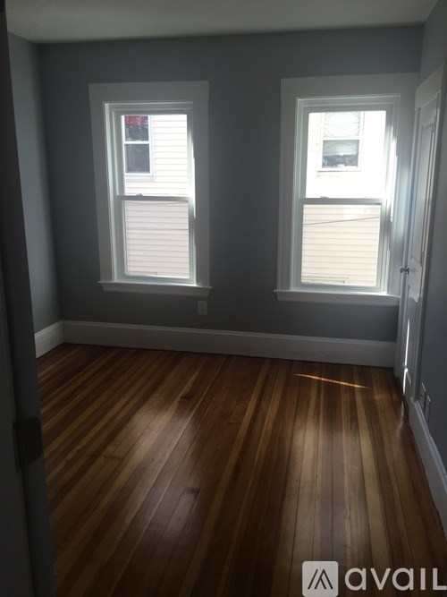A room with wooden floors and two windows.