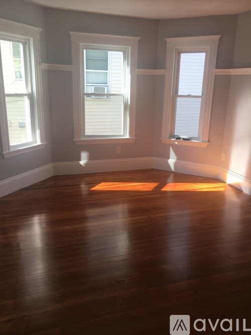 A room with wooden floors and three windows.