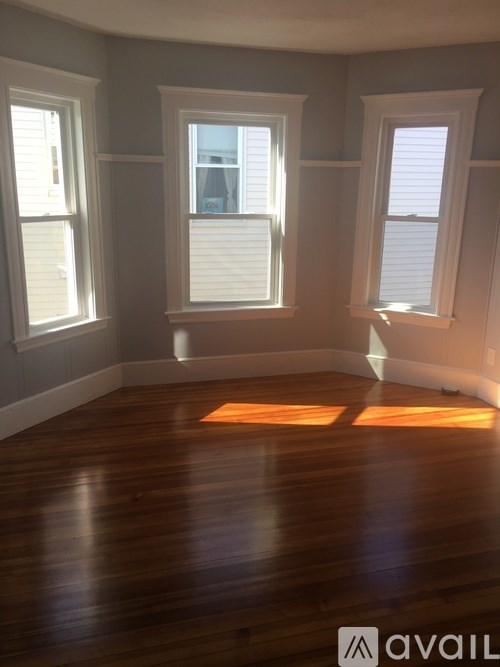 A room with wooden floors and three windows.