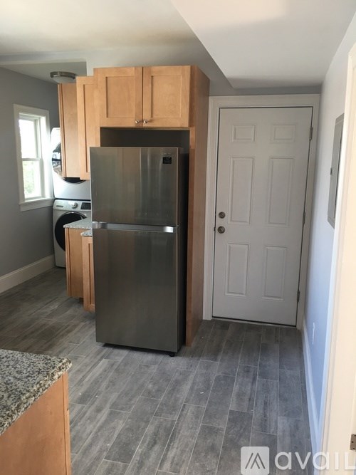 A kitchen with a refrigerator, cabinets, and a door.