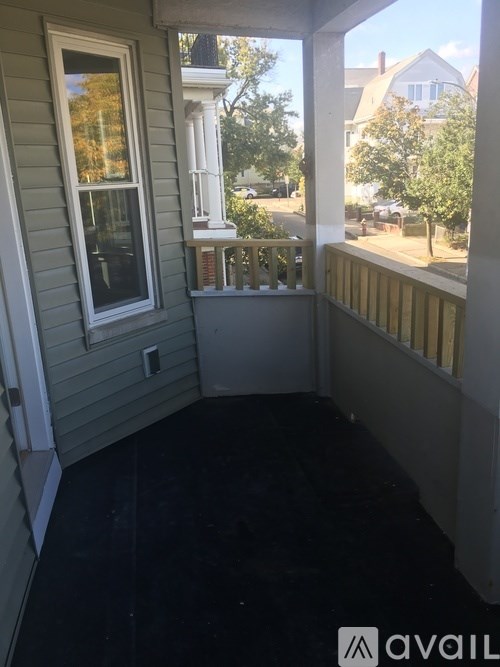 A balcony with a railing and a window overlooking a street.