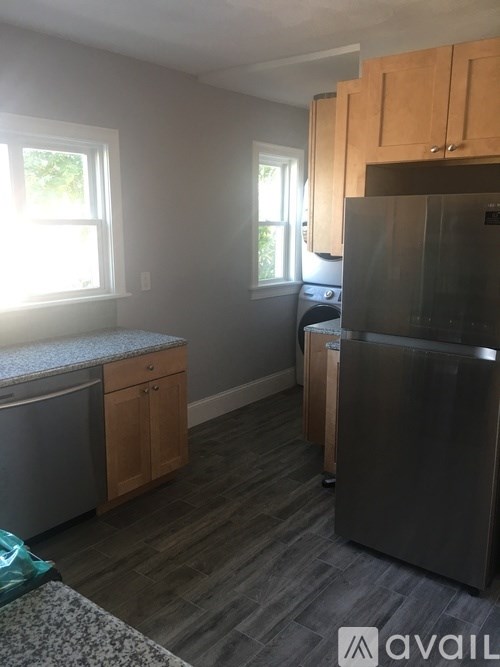 A kitchen with a black fridge, a dishwasher and wooden cabinets.