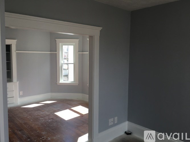 A room with a window and wooden floors is available for rent.
