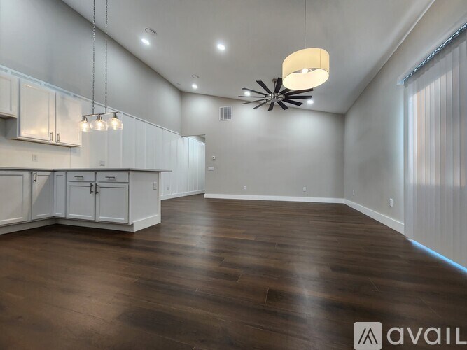 A spacious kitchen with white cabinets and a wooden floor.