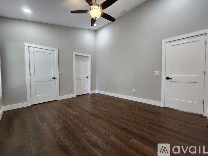 A room with a ceiling fan and wooden flooring.