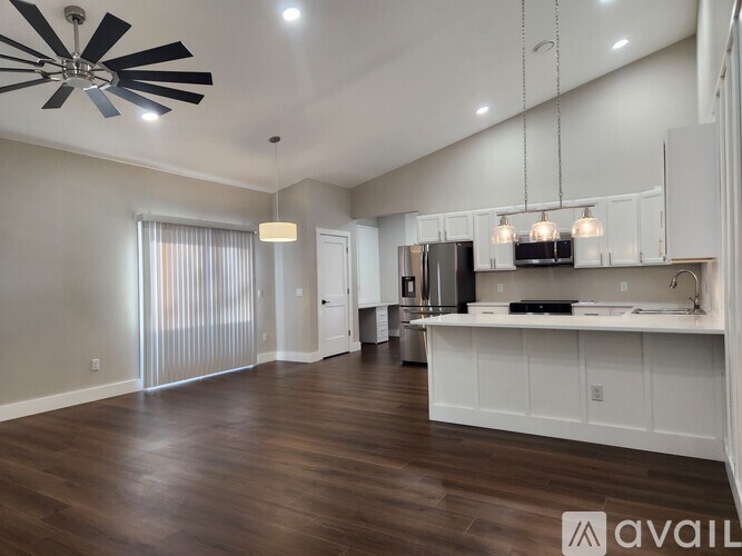 A spacious kitchen with white cabinets and a wooden floor.