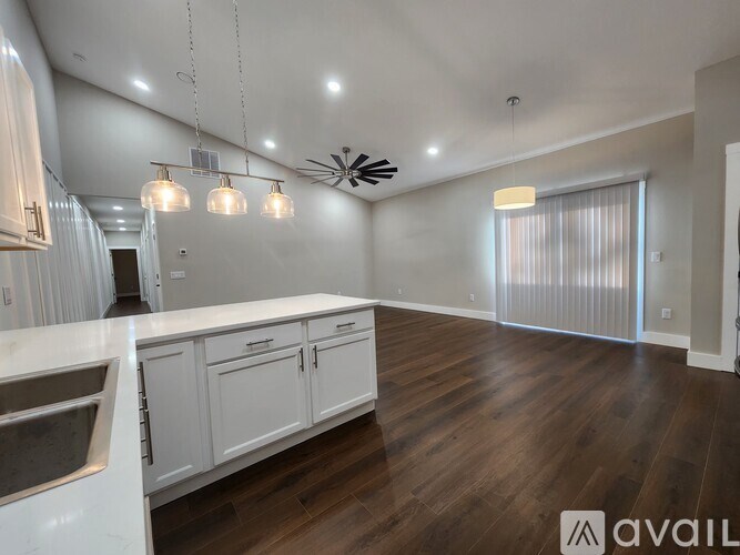 A modern kitchen with white cabinets and a wooden floor.