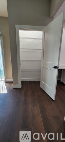 A room with a white door and wooden flooring.