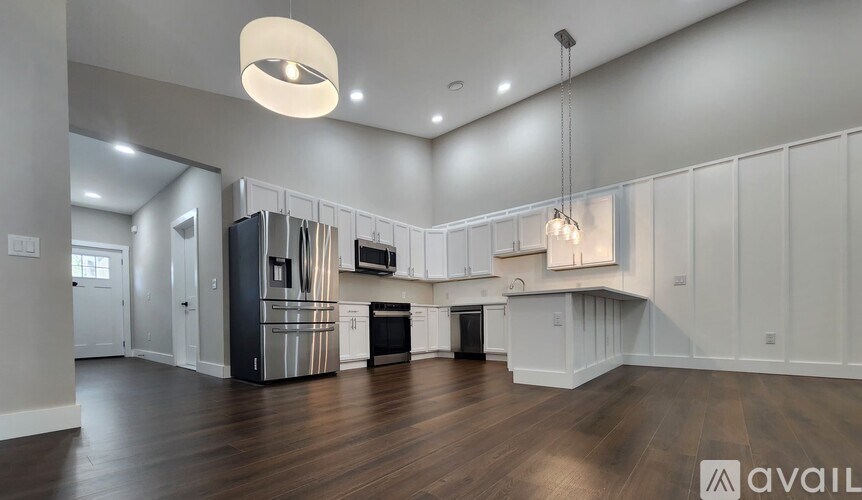 A modern kitchen with wooden floors and white cabinets.