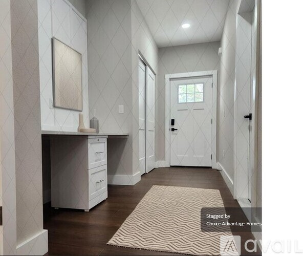 A hallway with a desk and drawers on the left and a door on the right.