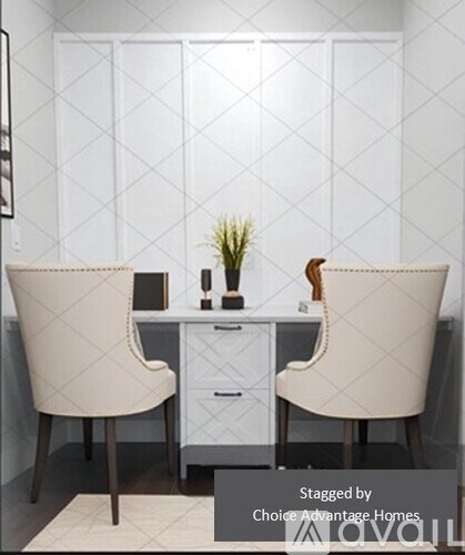 Two chairs are placed in front of a desk with a plant on it.