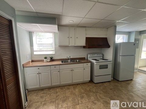 A kitchen with white cabinets and a tiled floor.
