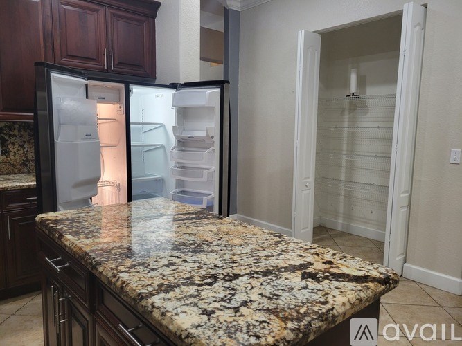 A kitchen with granite countertops and a black refrigerator.
