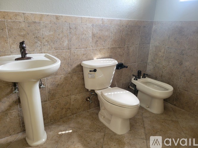 A bathroom with a sink, toilet and bidet.