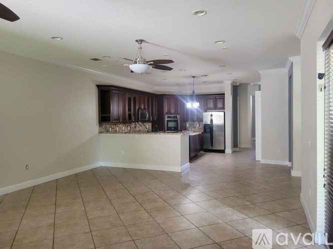 A spacious kitchen with dark wood cabinets and a ceiling fan.