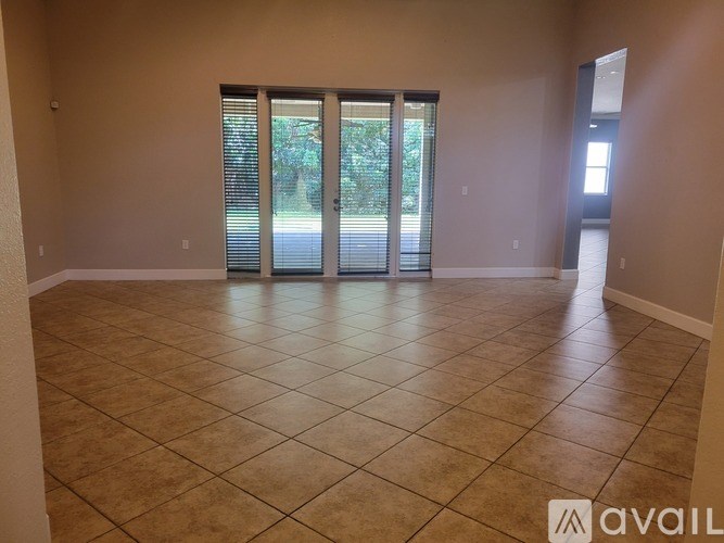 A spacious room with tiled flooring and sliding glass doors leading outside.