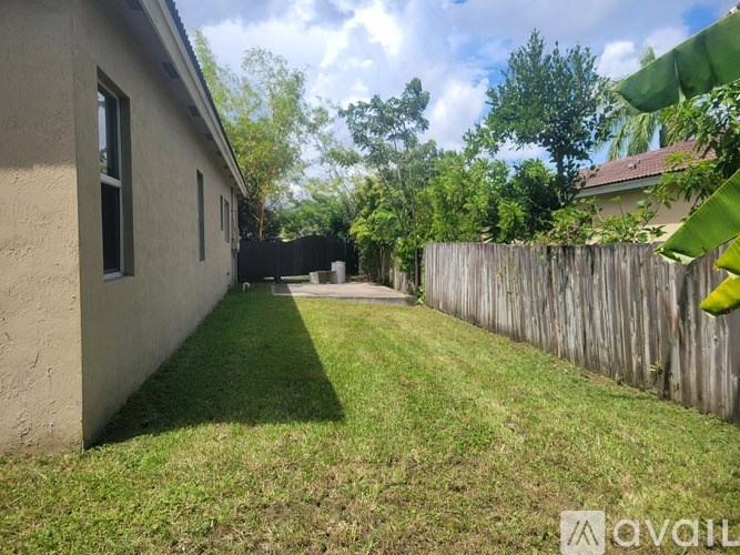 A backyard with a wooden fence and green grass.