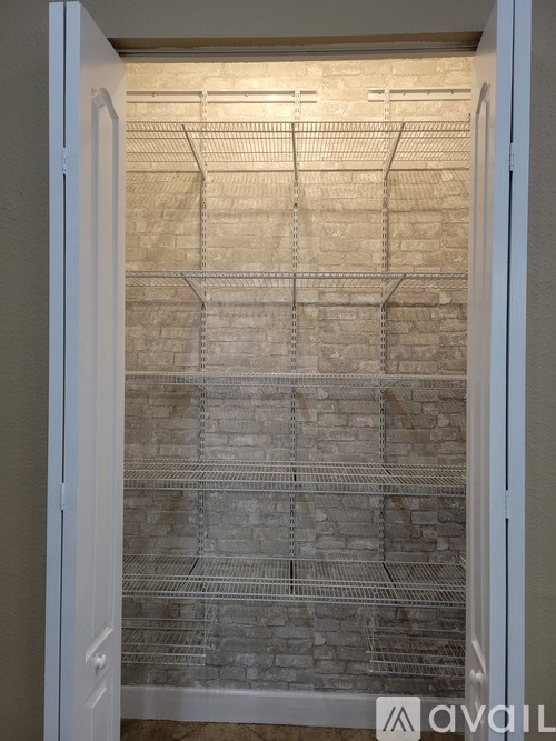 A white door is open to a room with a brick wall and a metal grid.