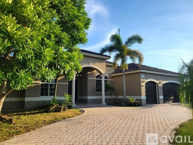 A house with a driveway and a tree in front of it.