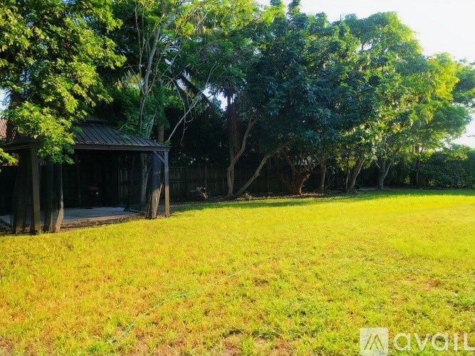 A grassy field with a wooden structure and trees in the background.