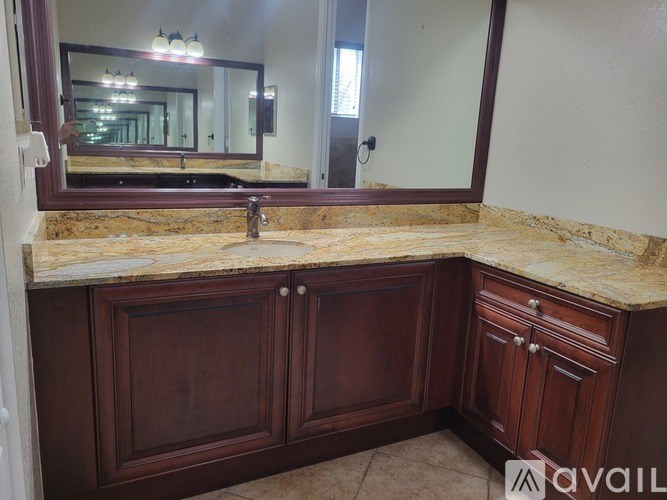 A bathroom vanity with a marble countertop and wooden cabinets.