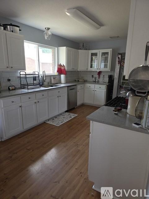 A kitchen with white cabinets and wooden floors.