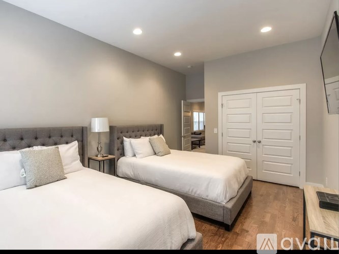 Two beds in a room with white bedding and grey headboard.
