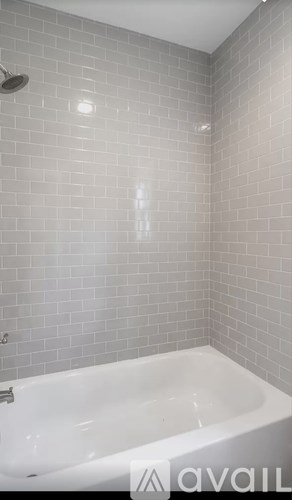 A white bathtub in a bathroom with grey tiles.