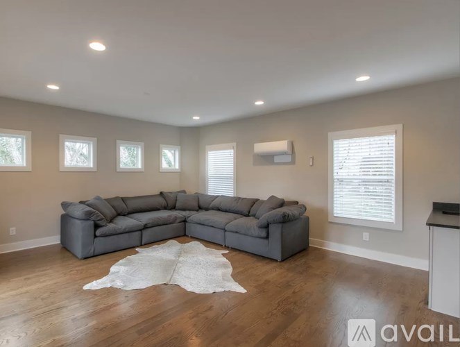 A spacious living room with a grey sectional sofa and a white cowhide rug.
