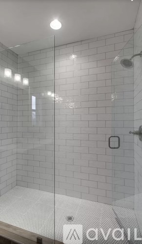 A glass shower door with a white tiled wall.